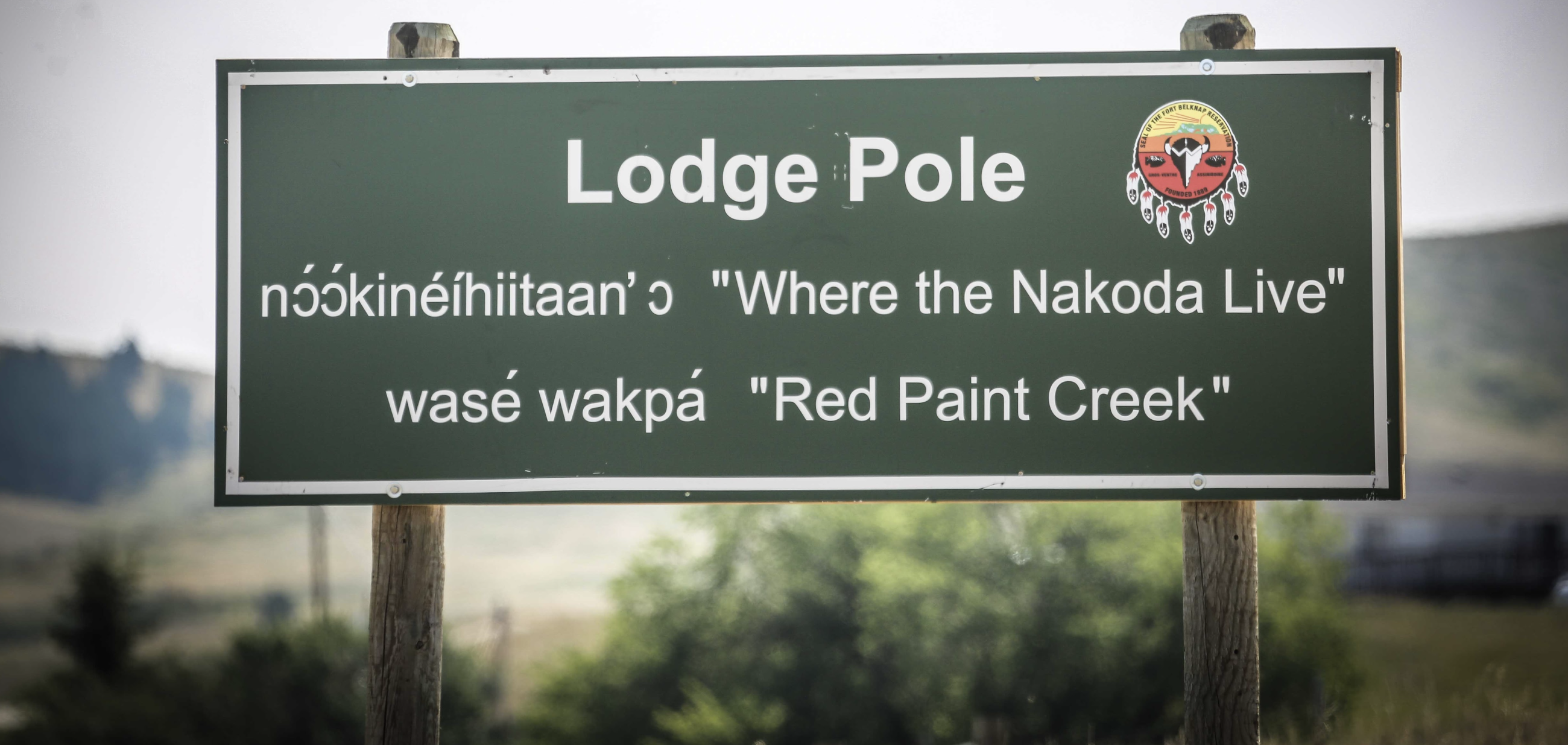 Photo of a sign that reads Lodge Pole, 'Where the Nakoda Live' and 'Red Paint Creek' in the Aaniih & Nakoda language